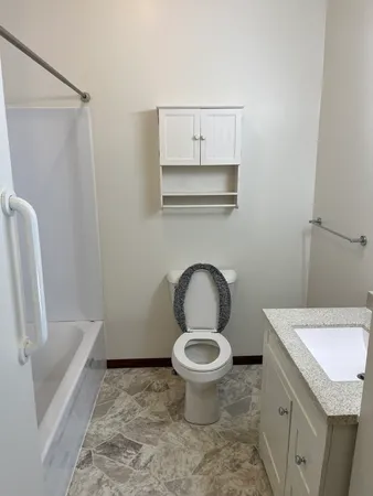 a bathroom with a granite countertop toilet and a sink