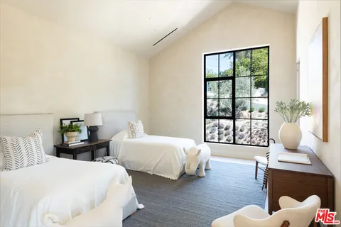 a bedroom with a bed and a large window with outer view