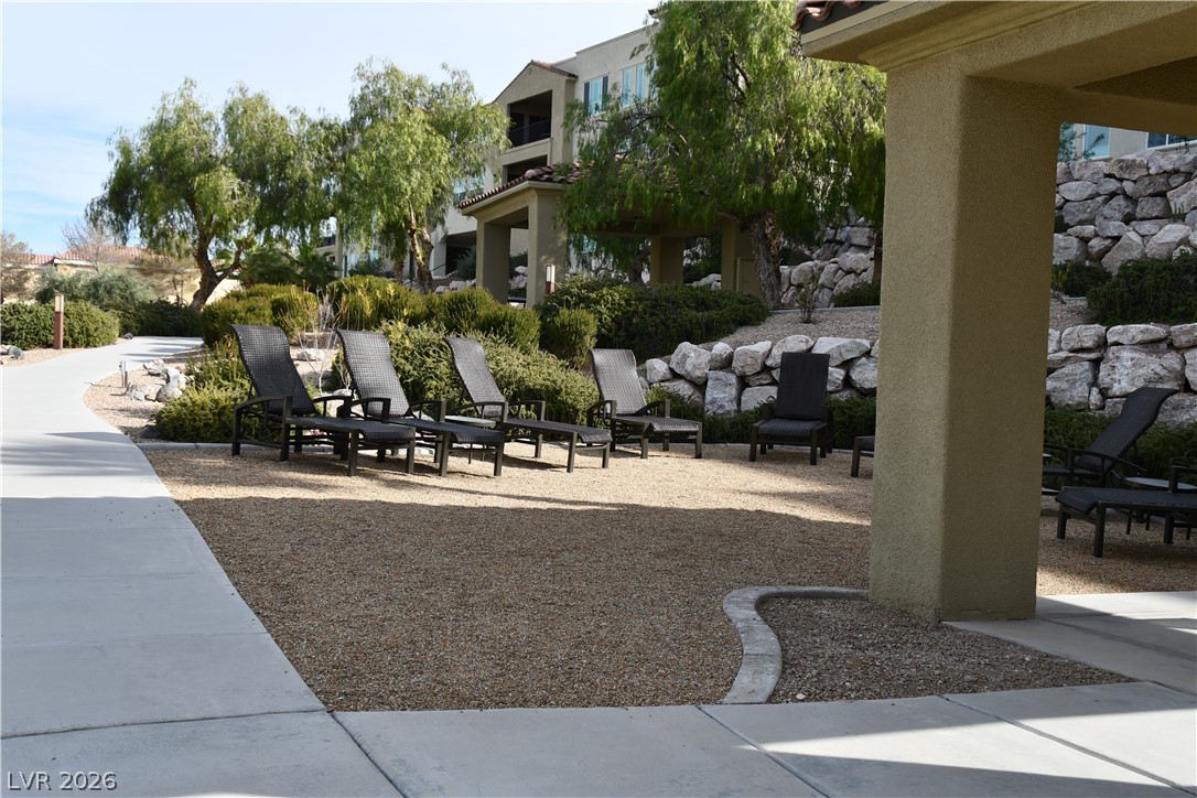 2555 Hampton Road, Unit 7109 Henderson, NV 89052 - Photo 6 of 34 Lounge chairs invite relaxation in a meticulously landscaped community outdoor space, with a winding pathway.