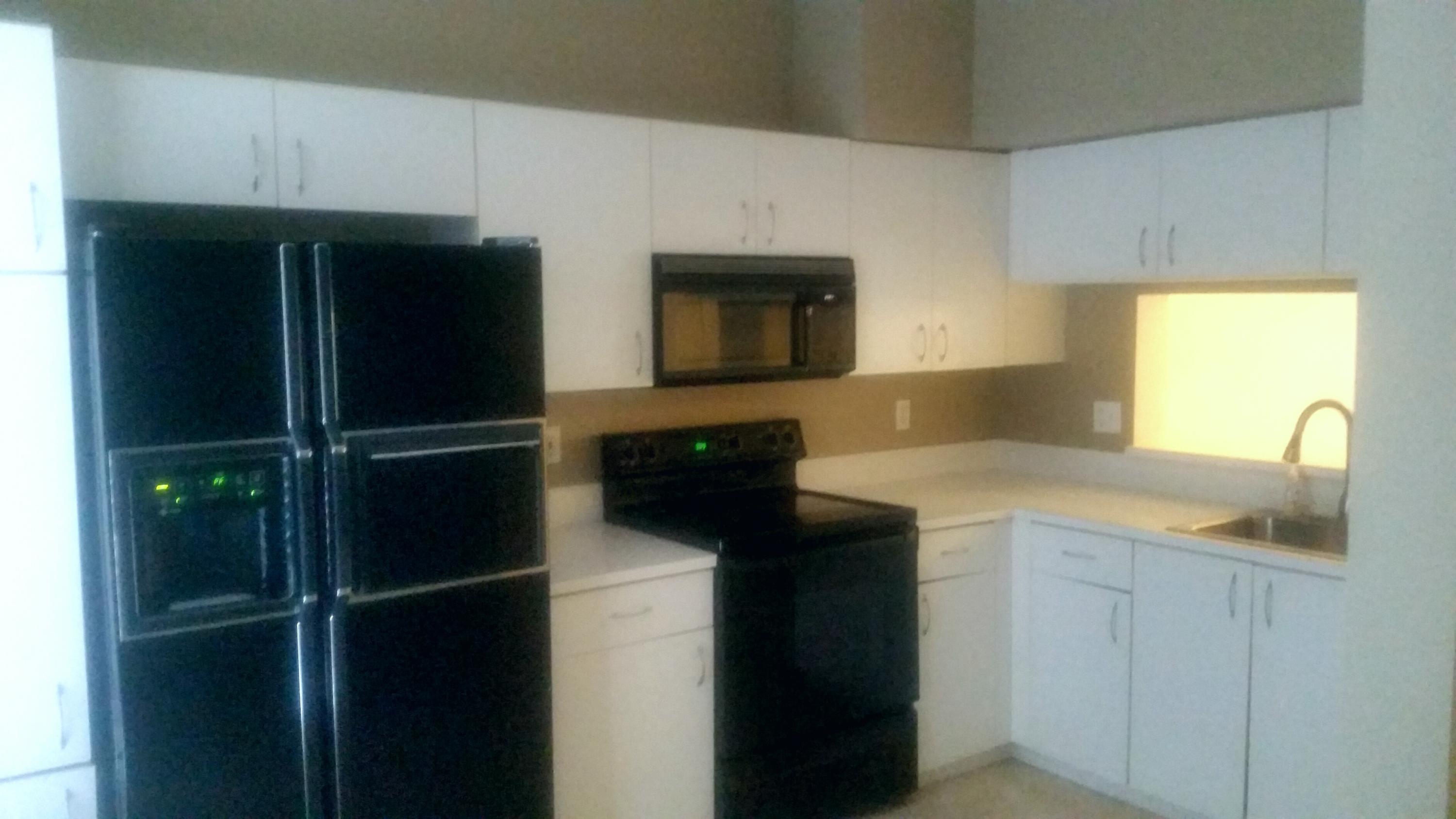 1004 Kokomo Key Lane Delray Beach, FL 33483 - Photo 7 of 21 a kitchen with a refrigerator and a sink