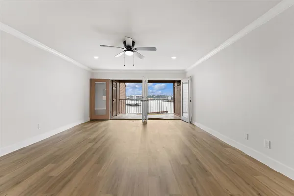 an empty room with wooden floor ceiling fan and windows