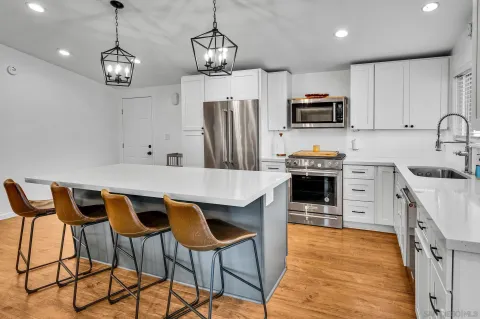 a kitchen with stainless steel appliances kitchen island granite countertop a sink a stove a microwave and a refrigerator