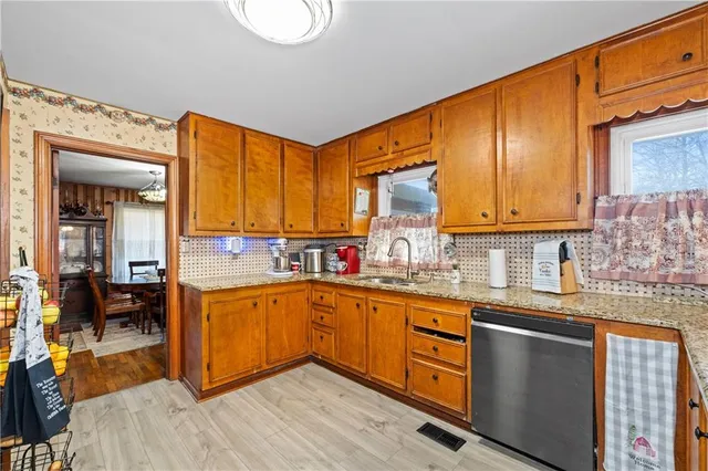 a kitchen with stainless steel appliances granite countertop wooden cabinets a sink and dishwasher a stove with wooden floor