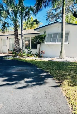 front view of house with a yard and palm trees