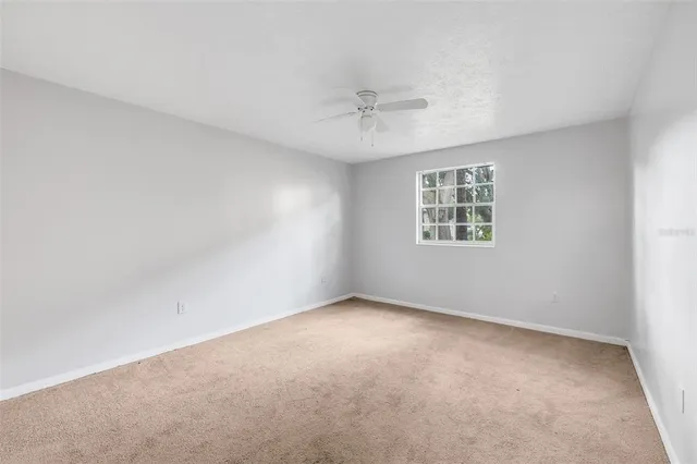 an empty room with a window and ceiling fan
