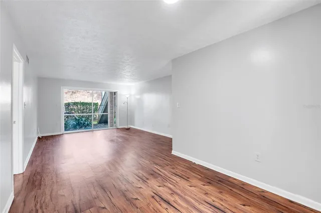 a view of empty room with wooden floor and fan