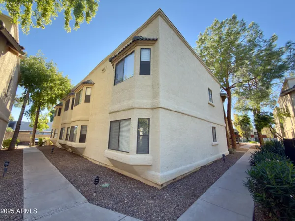 a view of a white house with a large tree