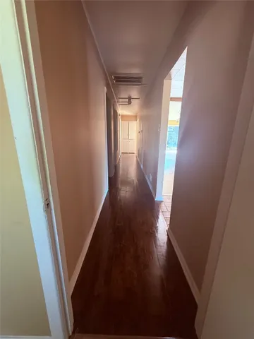 a view of a hallway with wooden floor and stairs