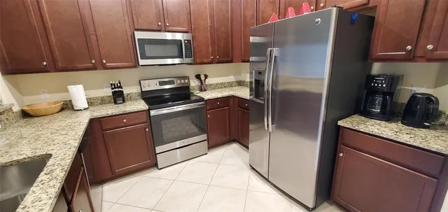a kitchen with granite countertop a refrigerator stove and microwave