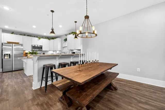 a dining room with wooden floor a chandelier a wooden table and chairs