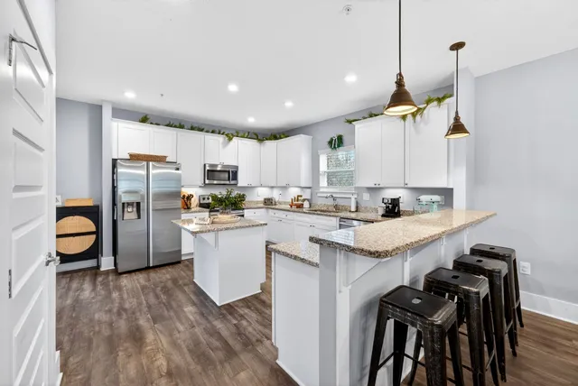 a kitchen with granite countertop white cabinets and stainless steel appliances