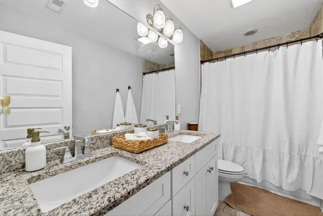 a bathroom with a granite countertop sink a toilet and a mirror