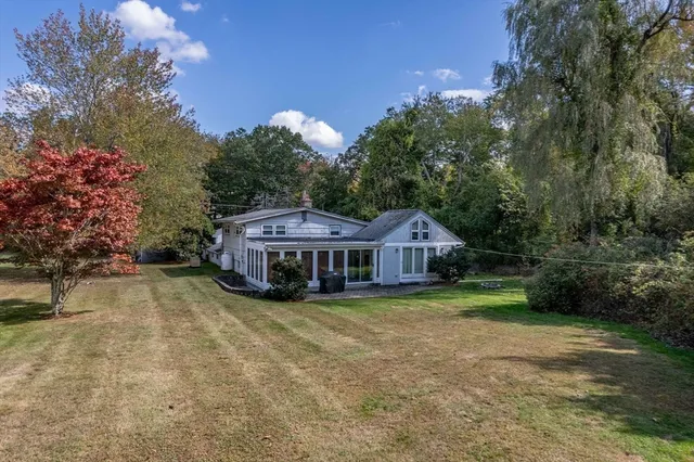 a view of a house with a yard and large trees