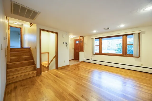 a view of an empty room with wooden floor and a window