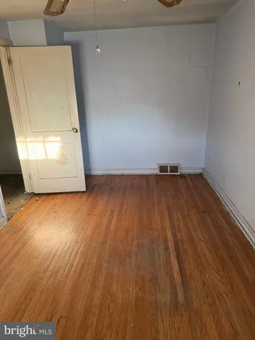 an empty room with wooden floor cabinet and windows