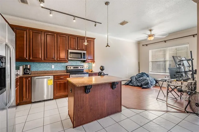 a kitchen with stainless steel appliances granite countertop a stove a sink dishwasher and a refrigerator with wooden cabinets