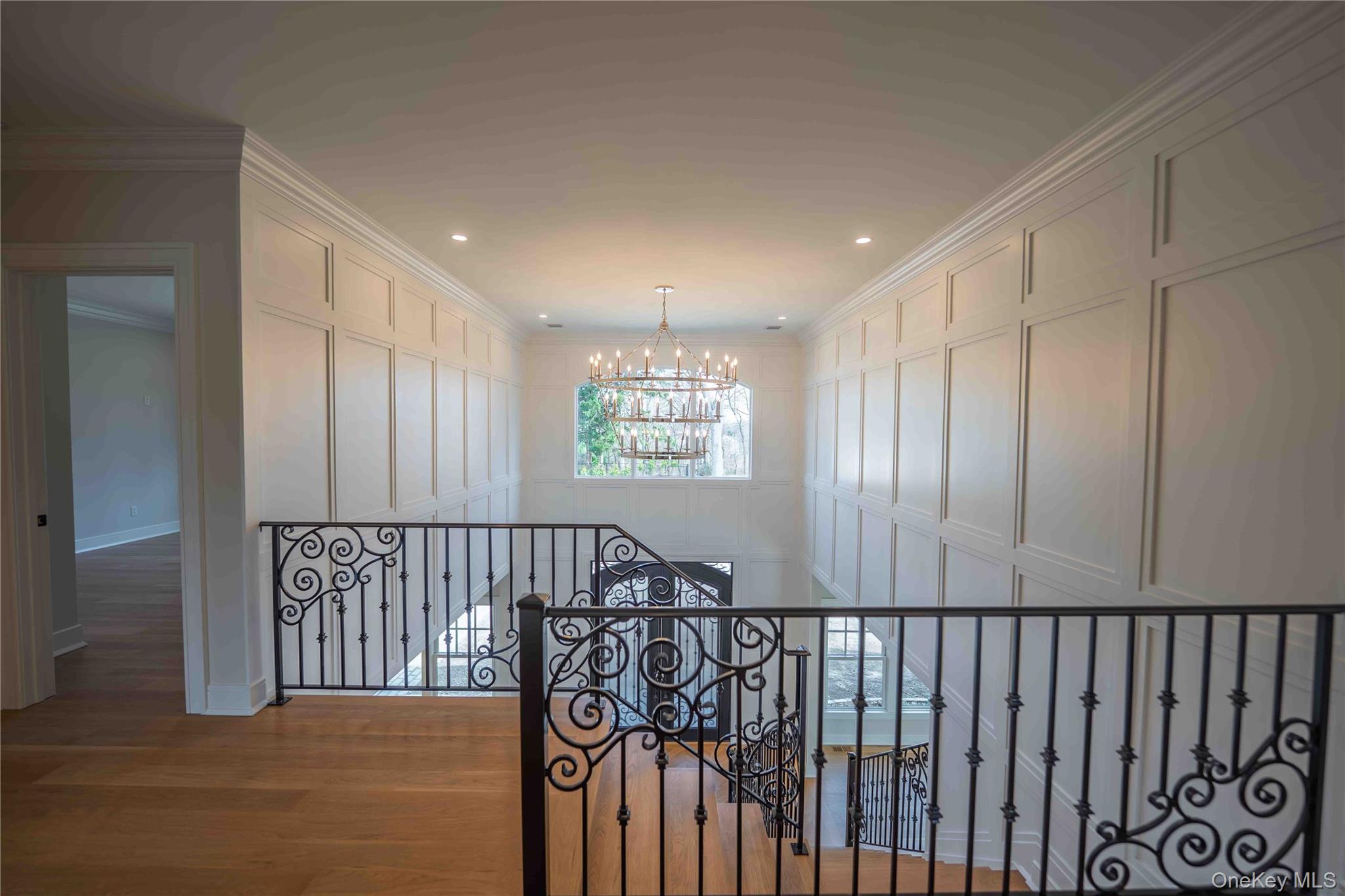 106 Cove Road Asharoken, NY 11768 - Photo 21 of 46 Hallway with a decorative wall, a chandelier, wood finished floors, ornamental molding, and an upstairs landing