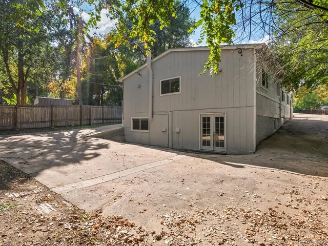 a backyard of a house with large trees and wooden fence