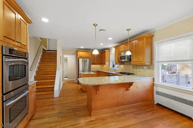 a large kitchen with stainless steel appliances granite countertop a stove and a wooden floors