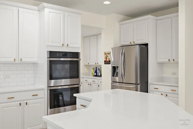 a kitchen with stainless steel appliances a refrigerator a stove and white cabinets