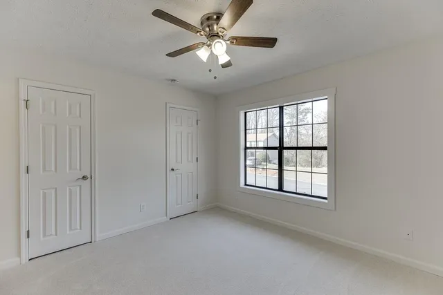 an empty room with a ceiling fan and a window