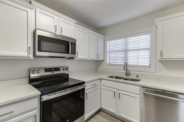 a kitchen with cabinets stainless steel appliances a sink and a window