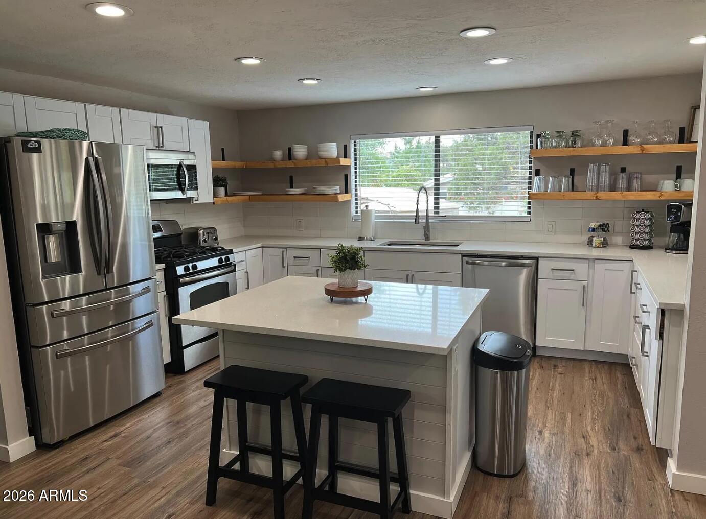 a kitchen with stainless steel appliances a table chairs refrigerator and wooden cabinets