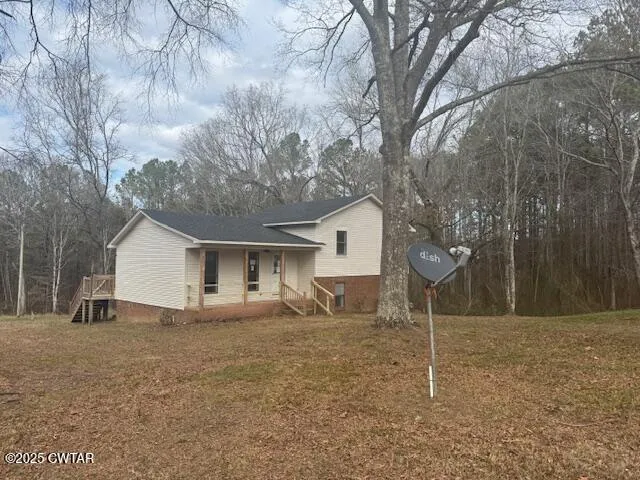 a backyard of a house with large trees and wooden fence
