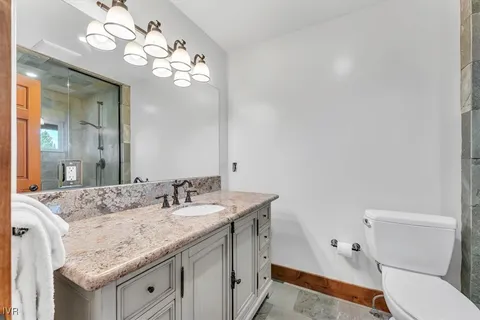 a bathroom with a granite countertop sink a toilet and a mirror