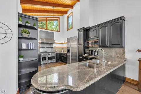 a kitchen with stainless steel appliances granite countertop a sink a stove and a refrigerator