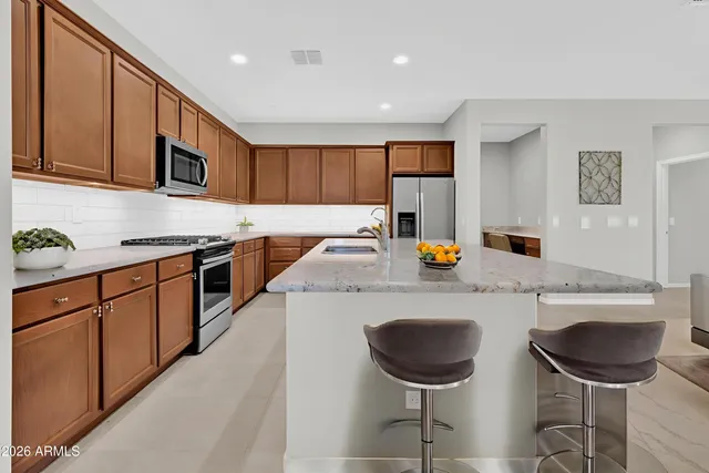 a kitchen with stainless steel appliances granite countertop a refrigerator a stove a sink a microwave a refrigerator and white cabinets with wooden floor