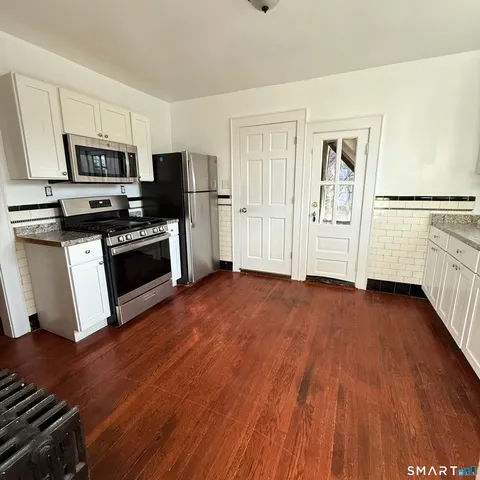 a view of kitchen with wooden floor and electronic appliances