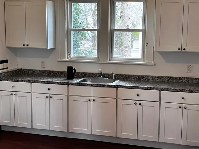 a kitchen with white cabinets and window