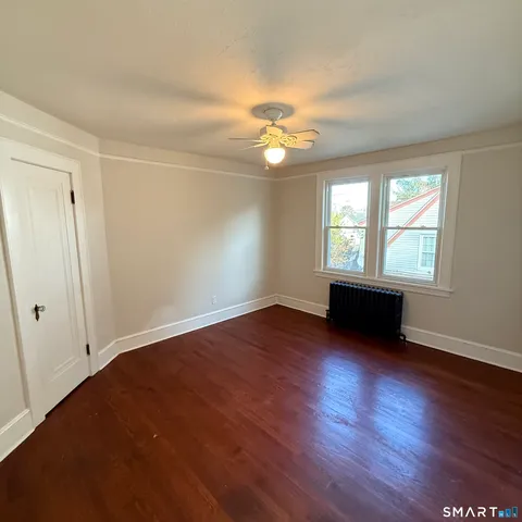 an empty room with wooden floor chandelier fan and windows