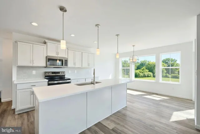 a kitchen with stainless steel appliances granite countertop a sink a window and white cabinets