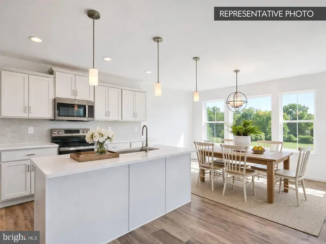 a kitchen with stainless steel appliances granite countertop a stove a sink a microwave a dining table and chairs with wooden floor