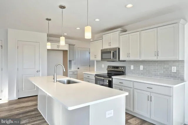 a kitchen with stainless steel appliances a sink a stove a microwave a center island and cabinets