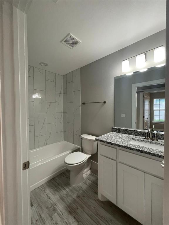 1315 West Gandy Street Denison, TX 75020 - Photo 11 of 19 a bathroom with a granite countertop sink a toilet a mirror and bathtub