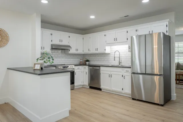 a kitchen with granite countertop a refrigerator sink and cabinets