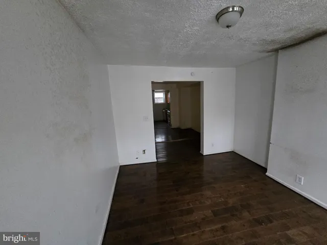 a view of a hallway with wooden floor and a bathroom