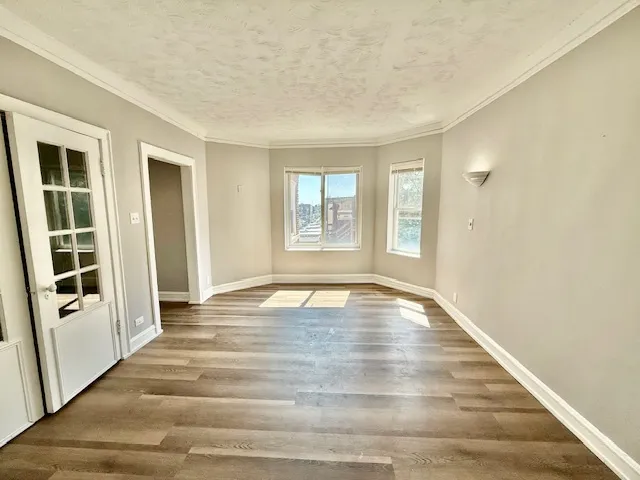 a view of an empty room with window and wooden floor