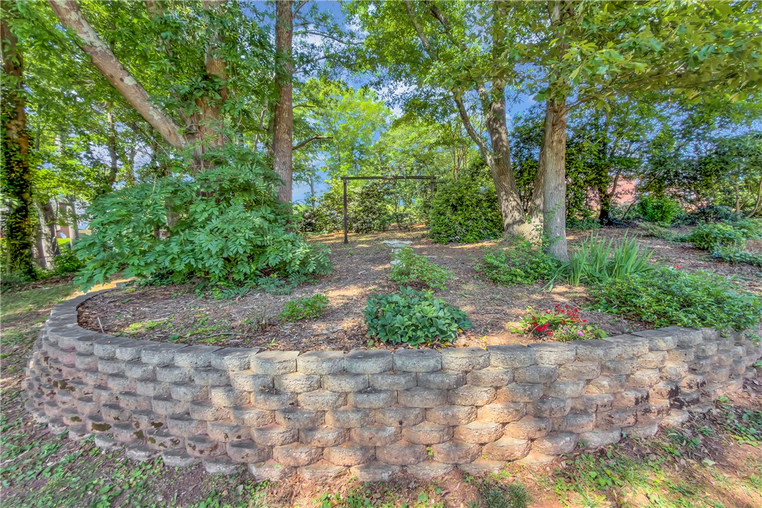 406 Hopewell Ridge Anderson, SC 29621 - Photo 43 of 46 This serene yard features mature trees, lush greenery, and a well-maintained stone retaining wall.