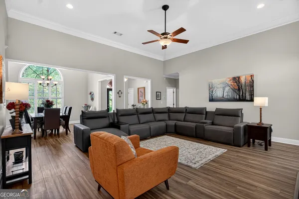 a living room with furniture kitchen view and a wooden floor