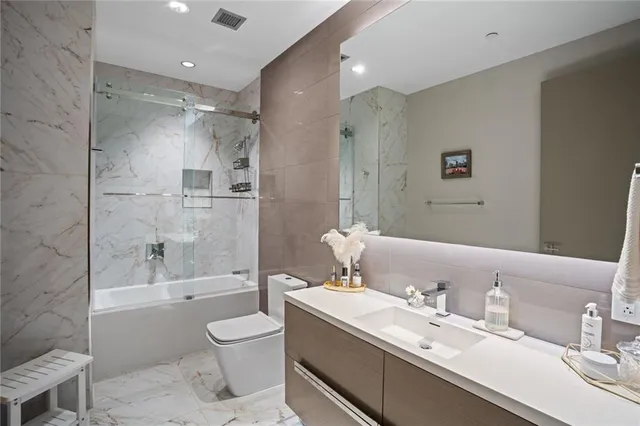 a bathroom with a bathtub shower sink mirror vanity and toilet