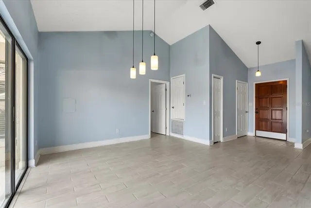 an empty room with chandelier fan and windows
