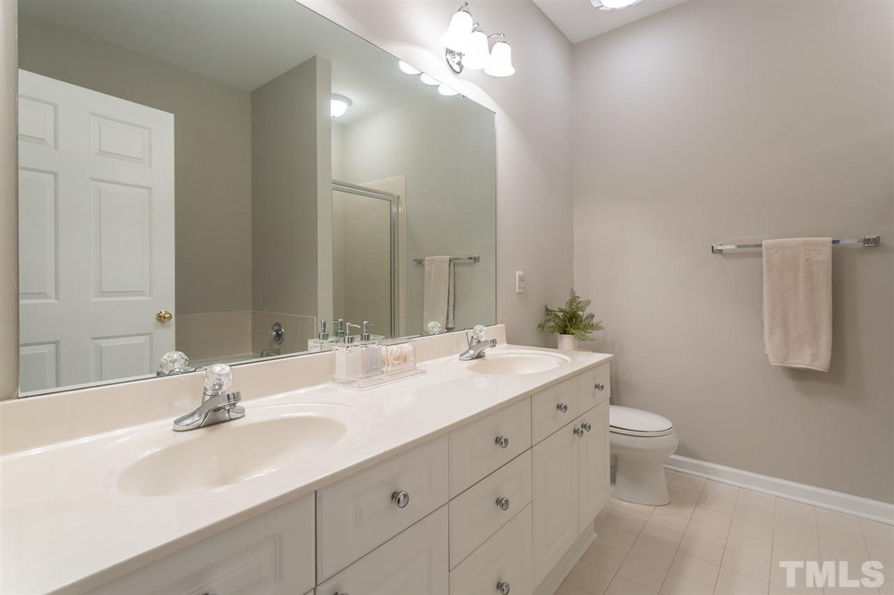 3151 Hemlock Forest Circle, Unit 102 Raleigh, NC 27612 - Photo 22 of 26 a bathroom with a double vanity sink a toilet and a mirror