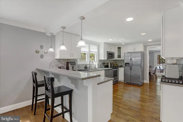 a kitchen with stainless steel appliances kitchen island a table chairs refrigerator and sink
