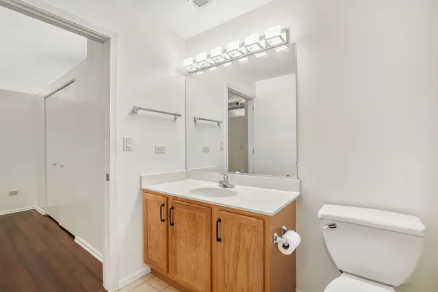 a spacious bathroom with a toilet a sink a mirror and vanity