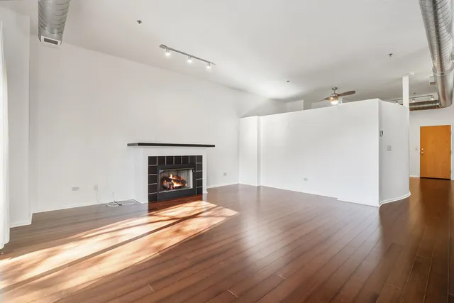 a view of an empty room with wooden floor fireplace and a window