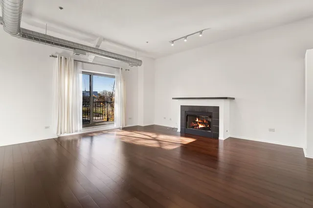 a view of an empty room with wooden floor fireplace and a window